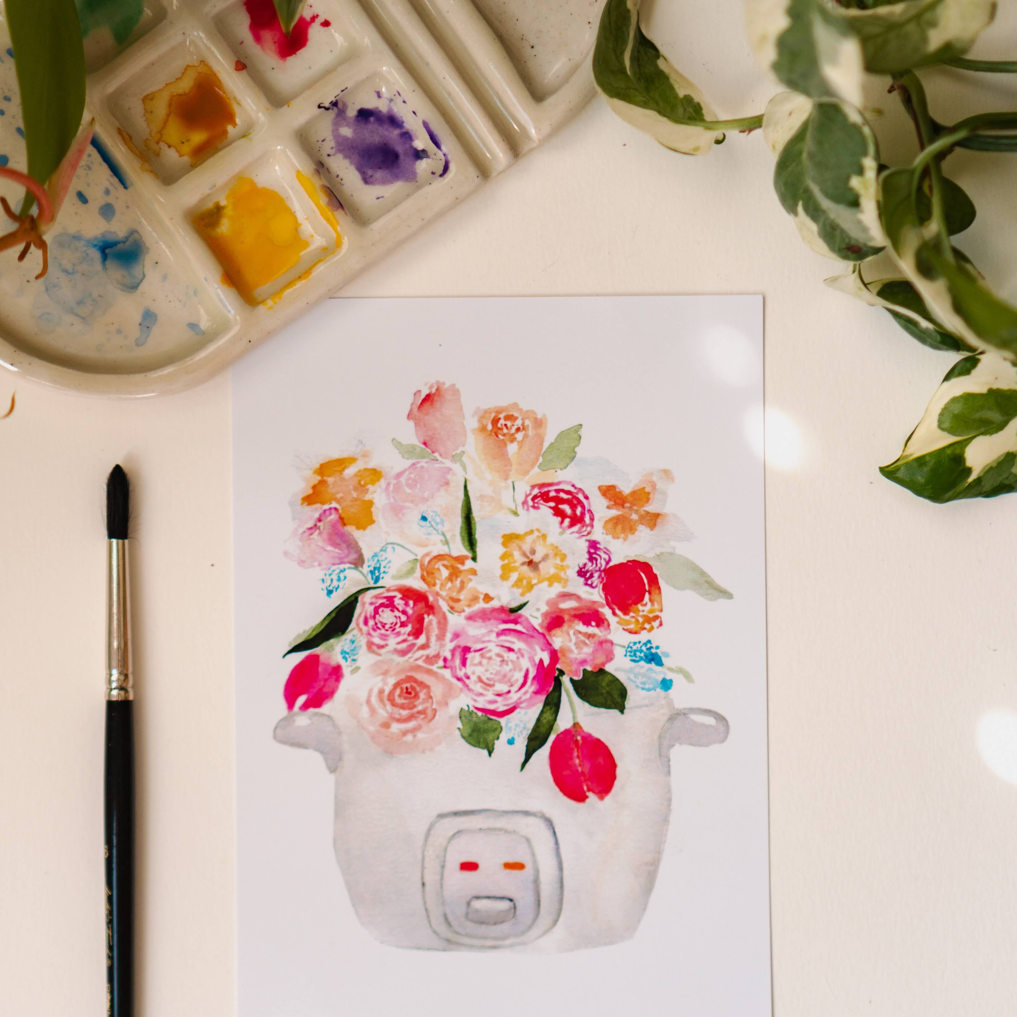 A pink, blue, and white print of a bouquet of tulips, roses, and other flowers sprouting out of a rice cooker.