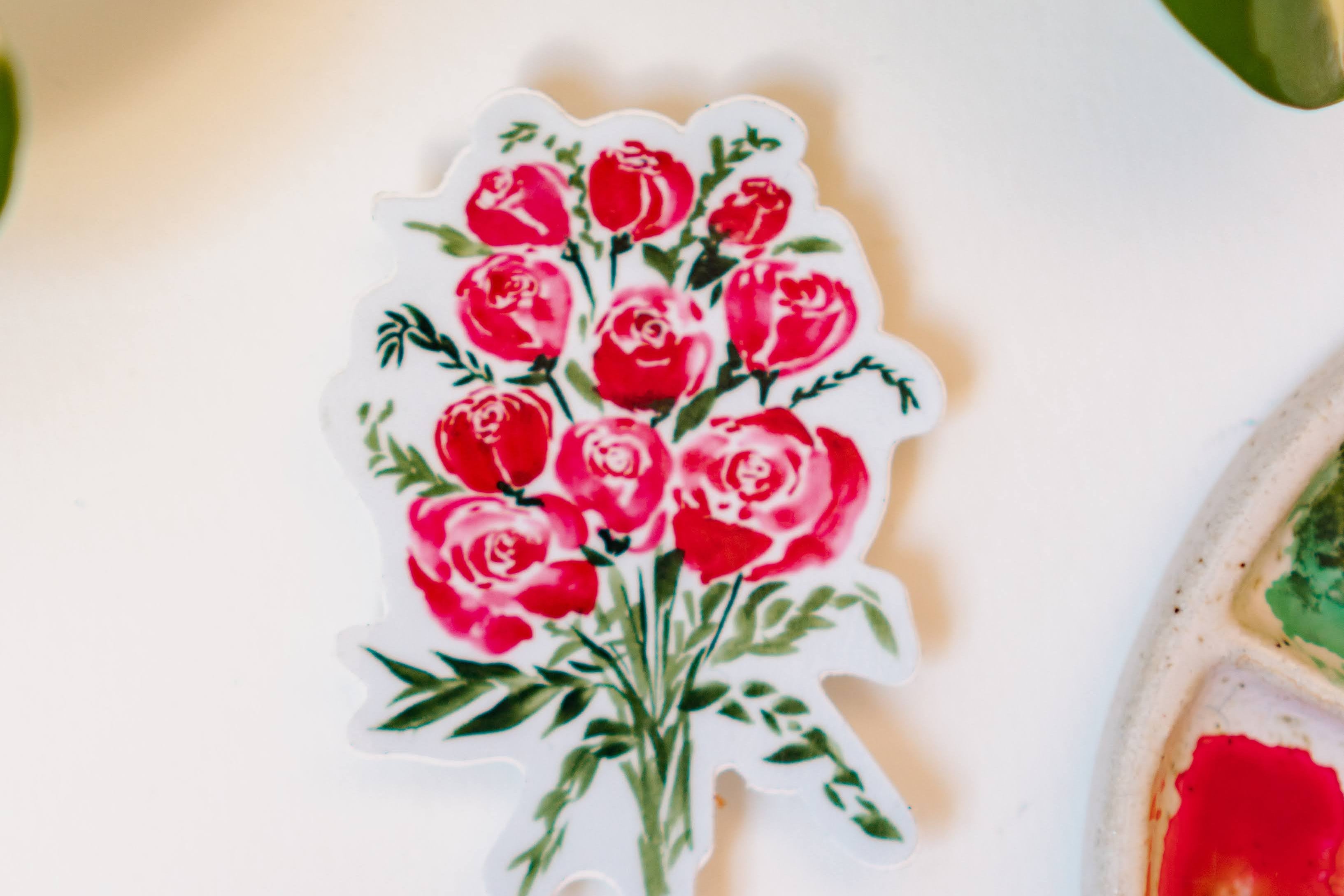 A sticker depicting a watercolor bouquet of red roses and small green bunches of leaves.