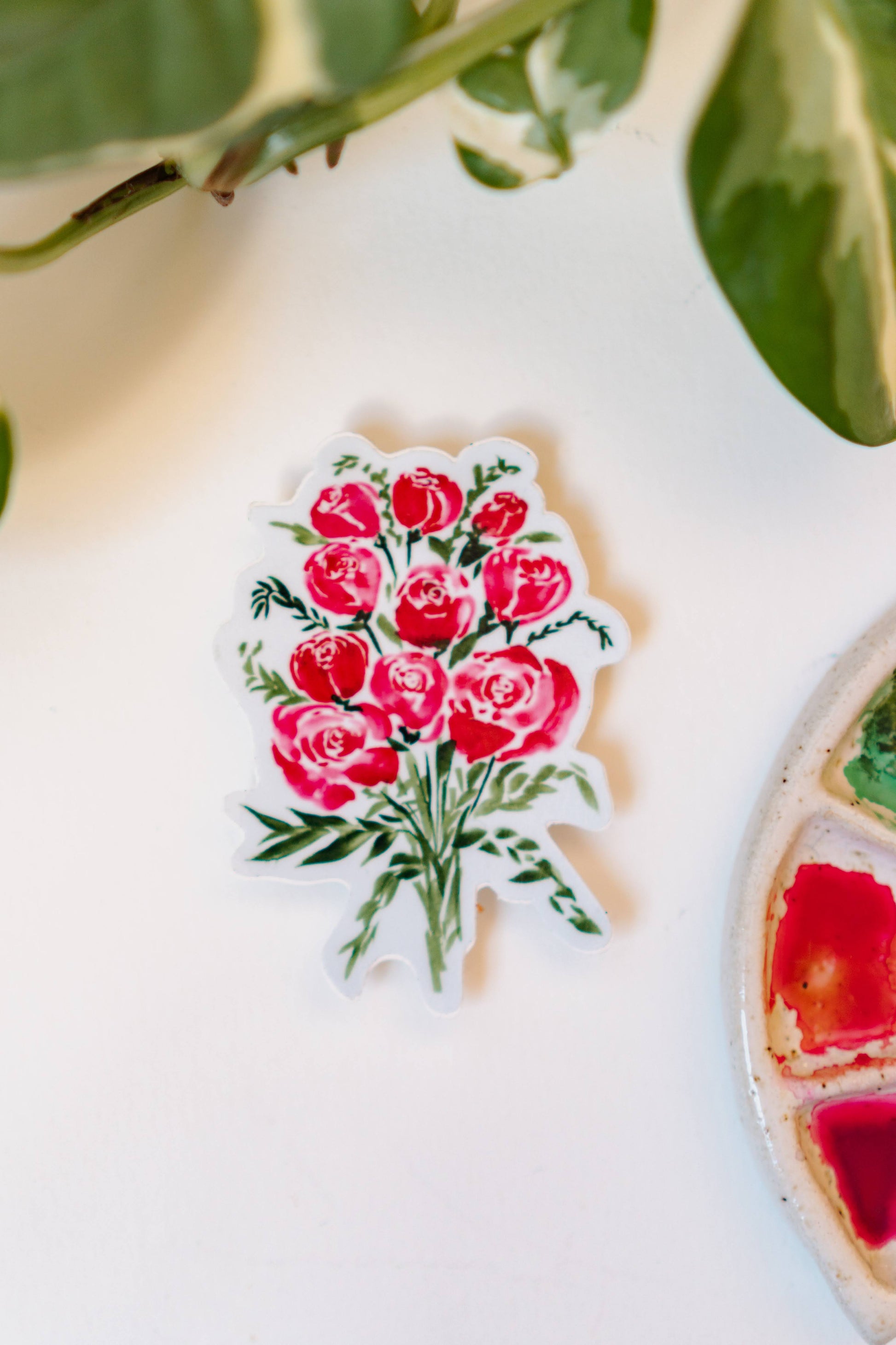 A sticker depicting a watercolor bouquet of red roses and small green bunches of leaves.