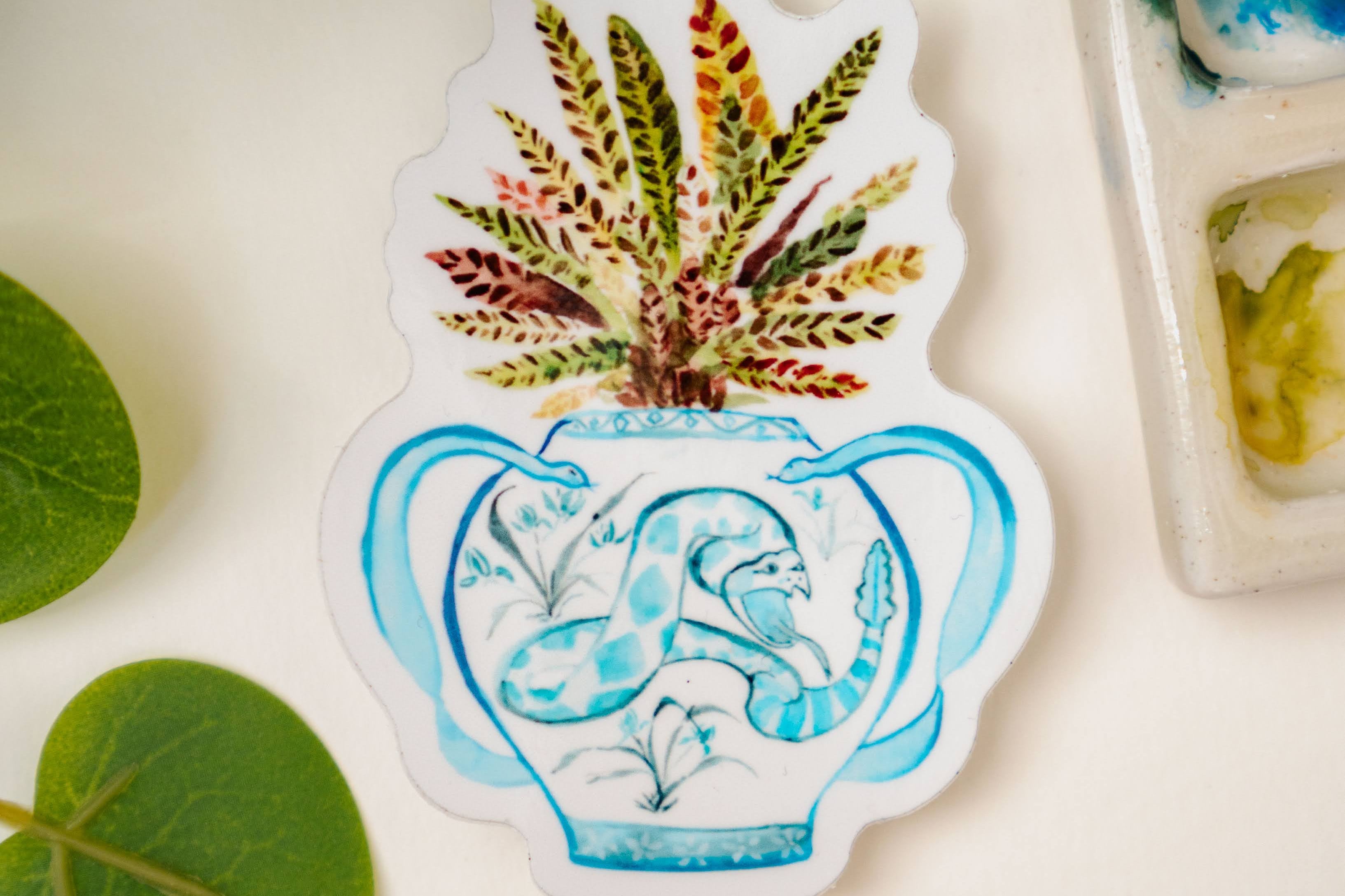 A print of a rattlesnake plant in a blue and white porcelain vase, decorated with a snake.