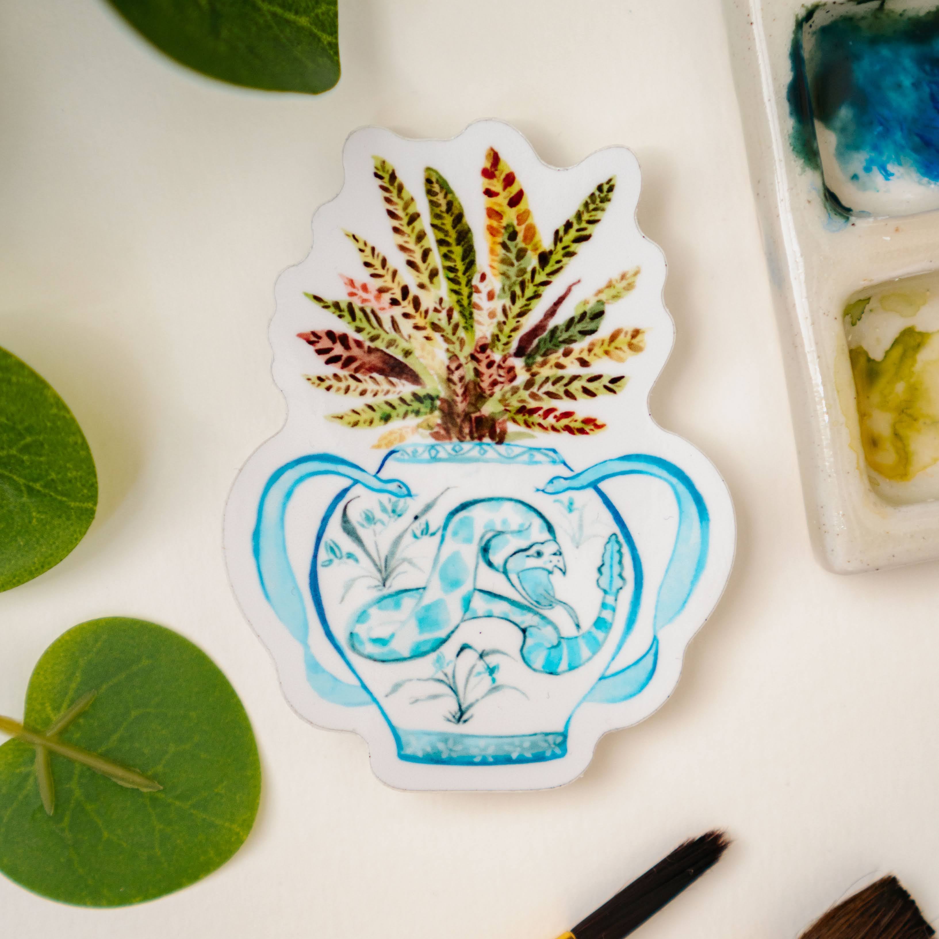 A print of a rattlesnake plant in a blue and white porcelain vase, decorated with a snake.
