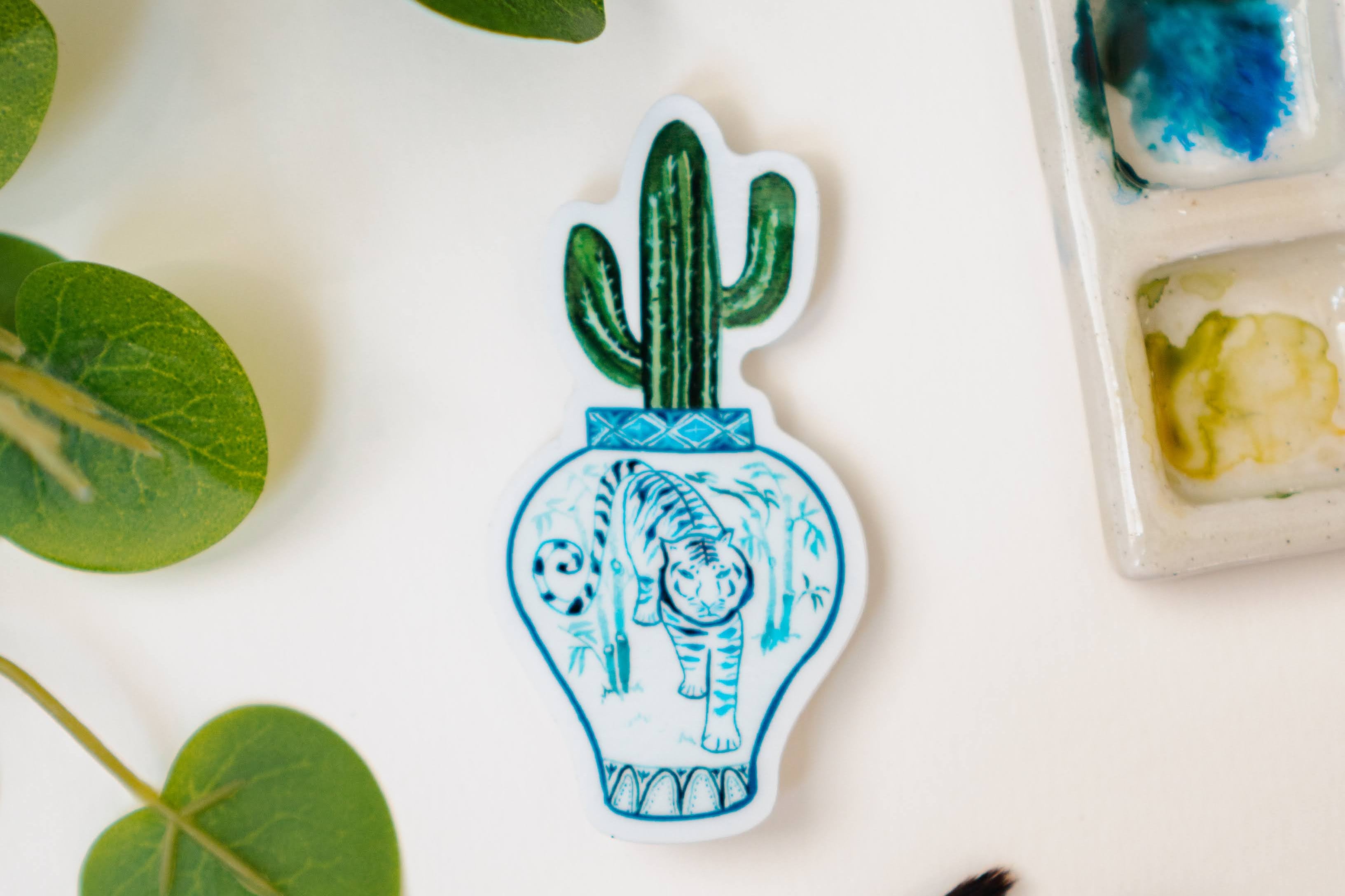 A sticker of a saguaro cactus in a blue and white porcelain vase, decorated with a tiger.