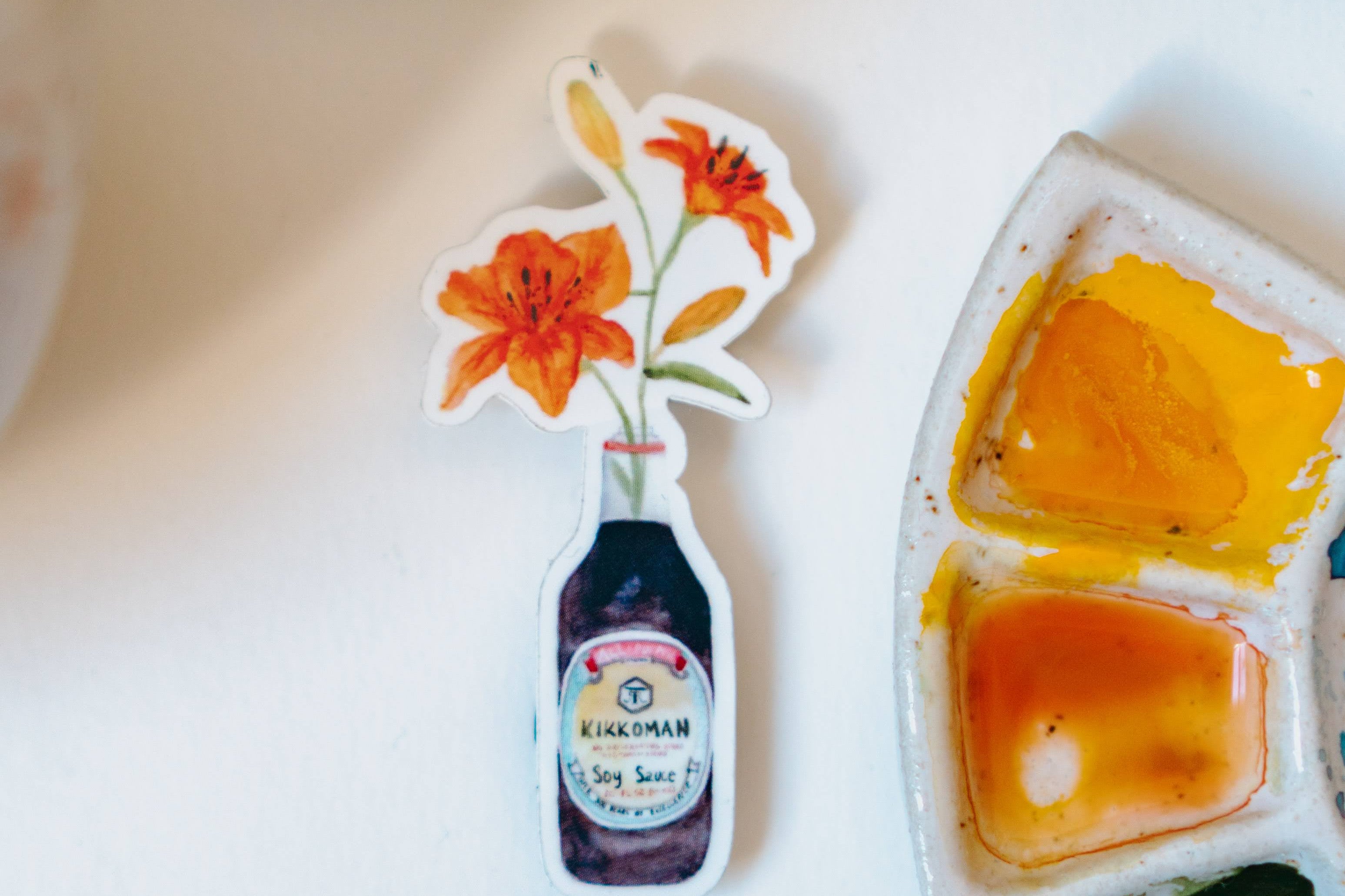 A watercolor sticker of two orange tiger lilies in a Kikkoman soy sauce bottle.