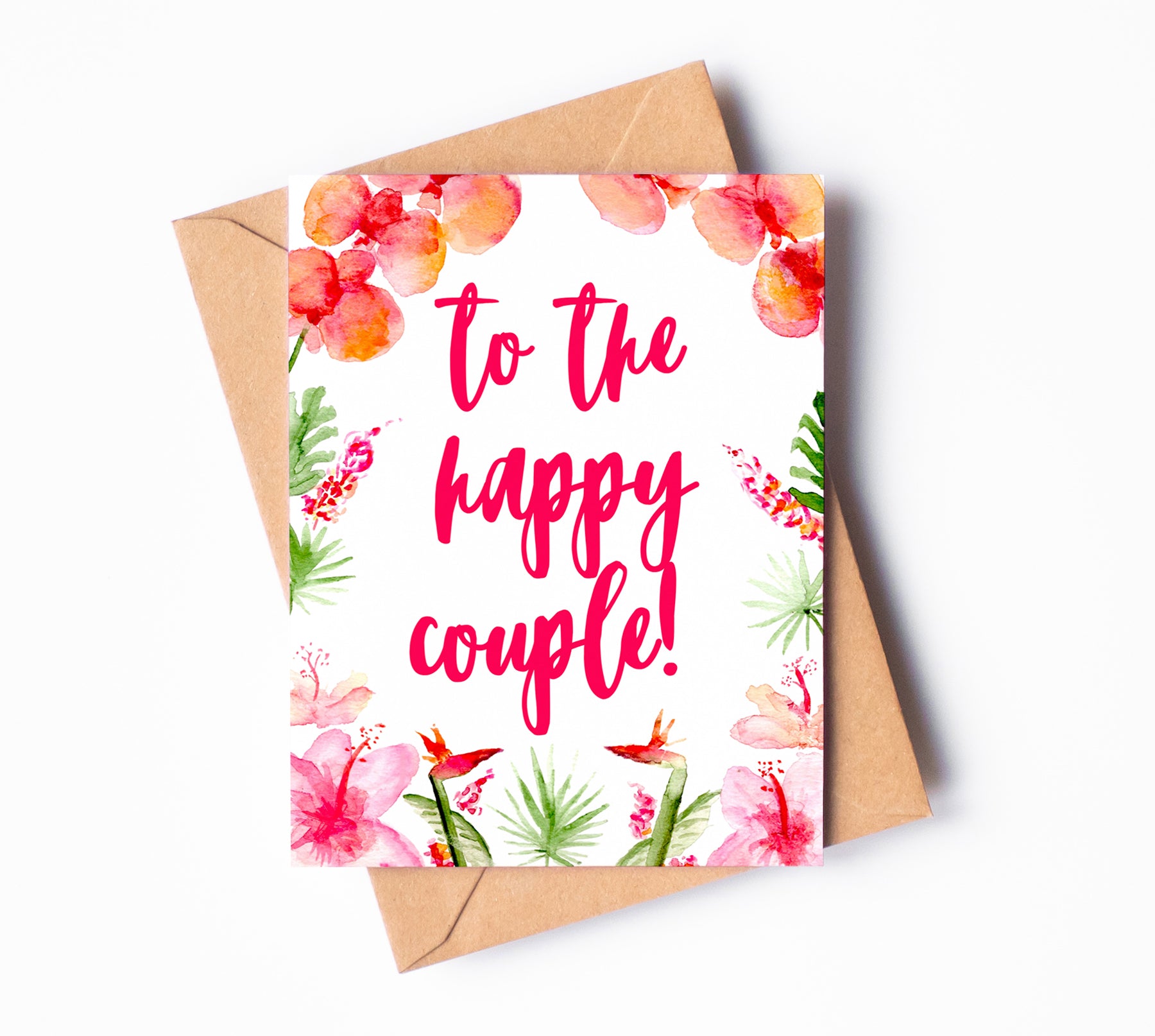 A greeting card with pink orchids, hibiscuses, and other tropical flowers. The phrase "to the happy couple!" is written in pink, cursive letters in the center of the card.