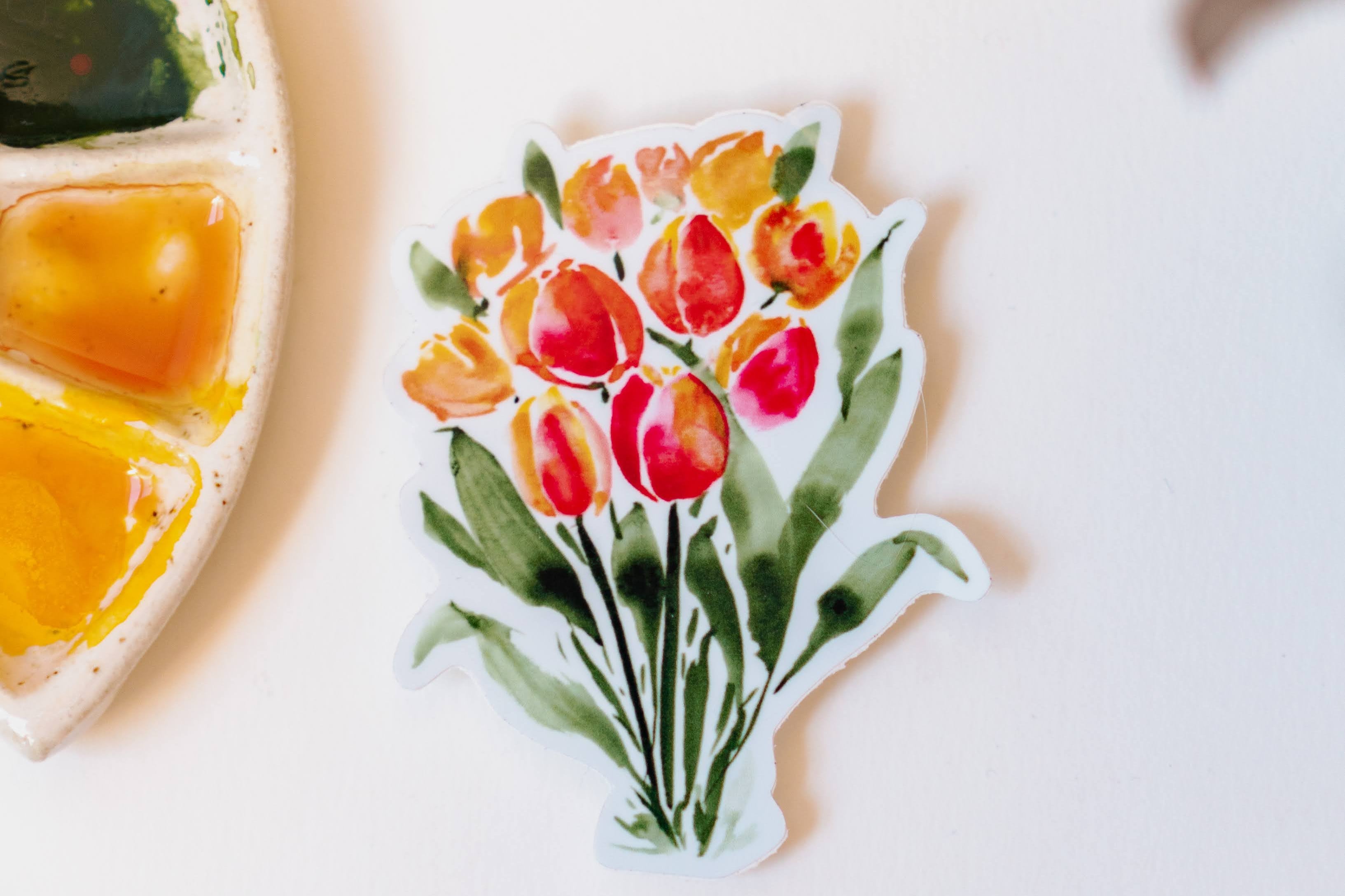 A sticker of orange and red watercolor tulips, standing on dark green stems.