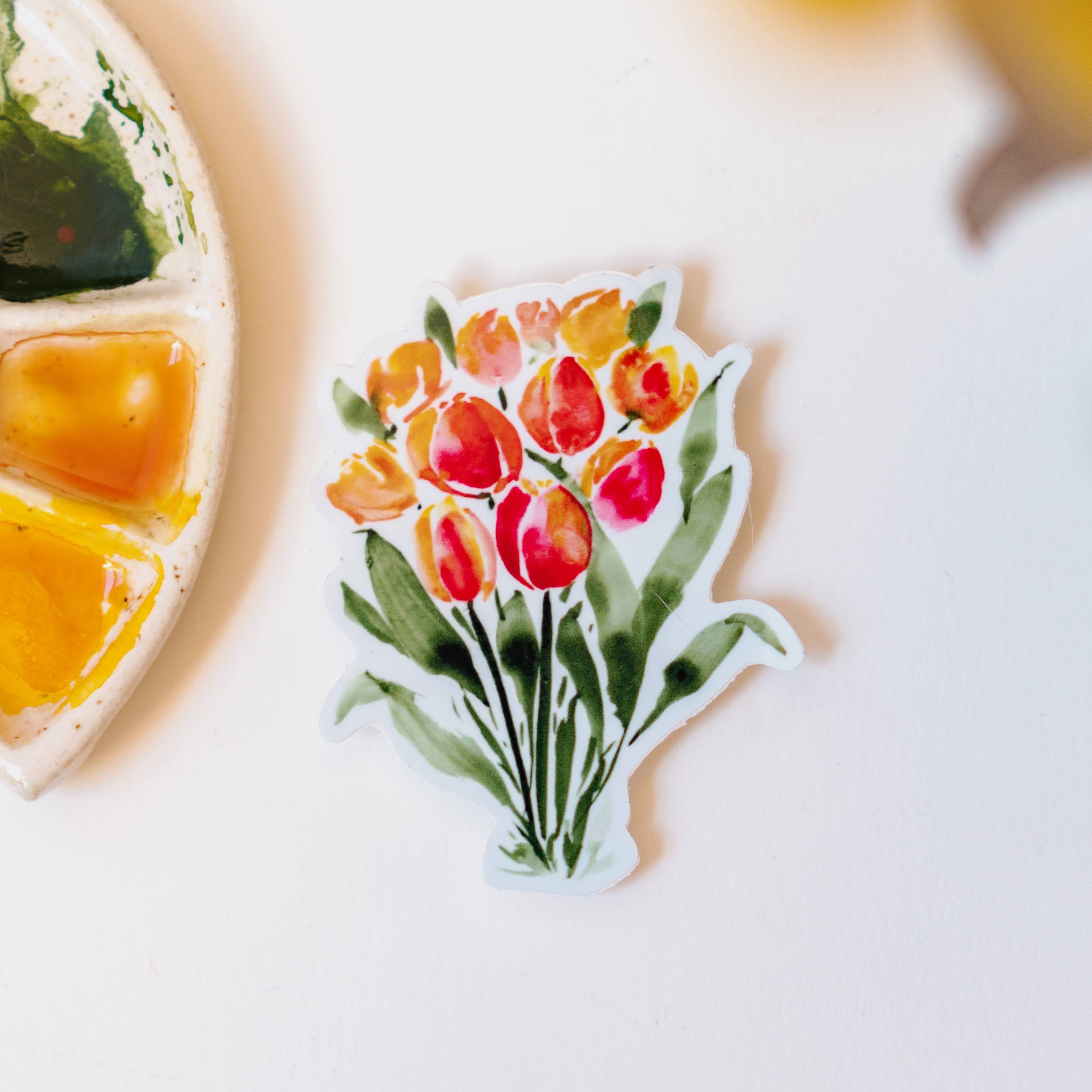 A sticker of orange and red watercolor tulips, standing on dark green stems.