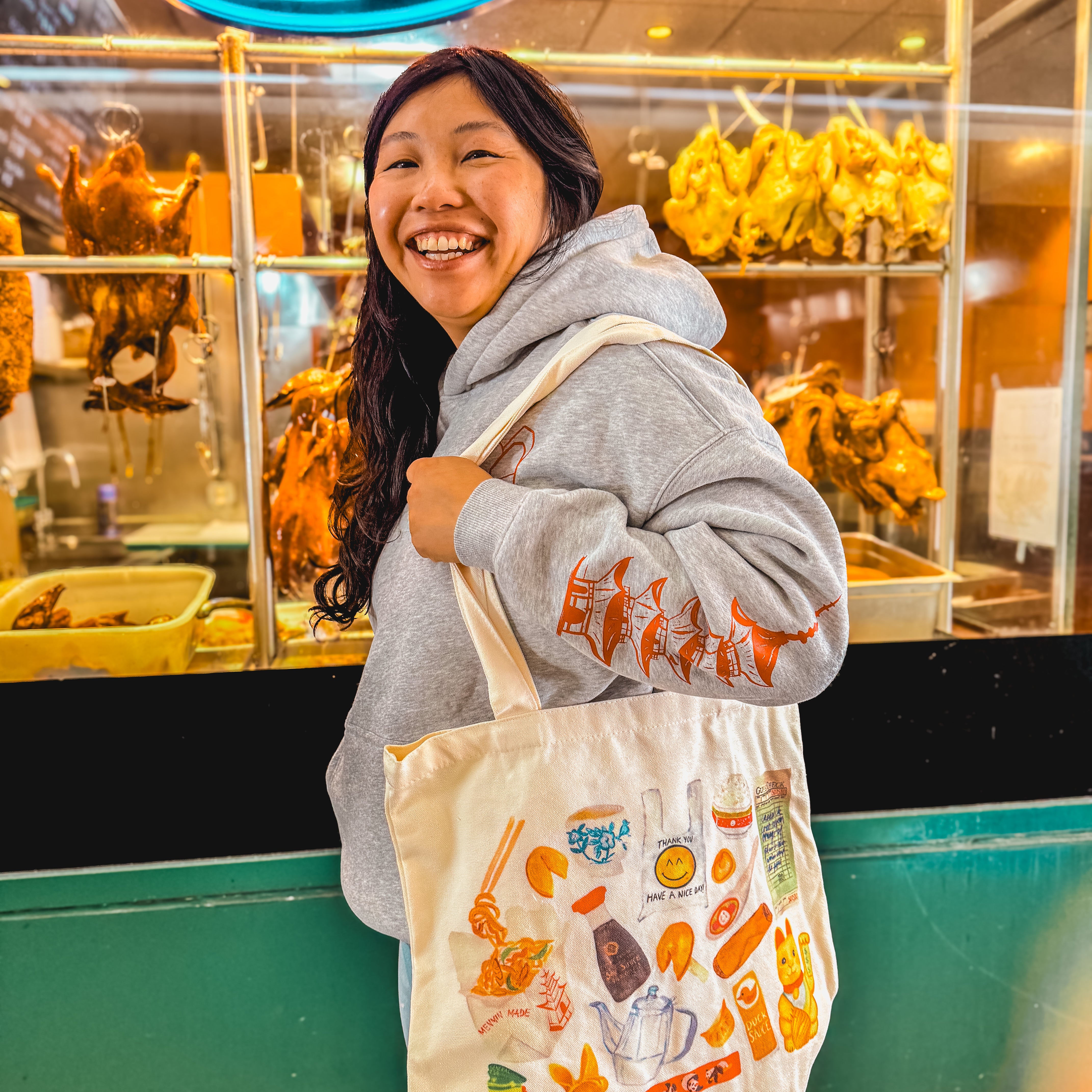 women smiling carrying a tote bag with watercolor of classic Chinese takeout restaurant items