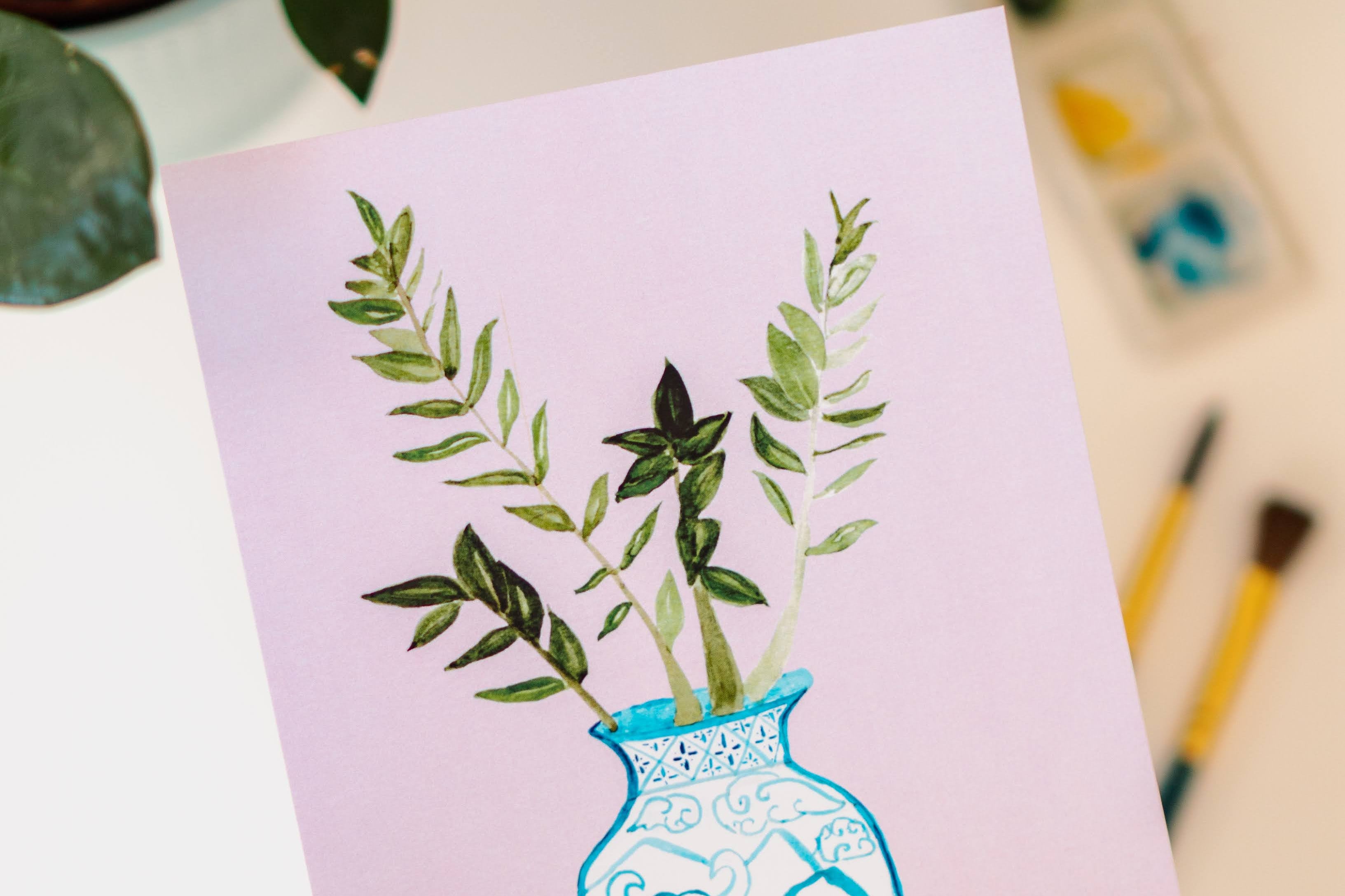 A print of a ZZ plant in a blue and white porcelain vase, decorated with an ox.