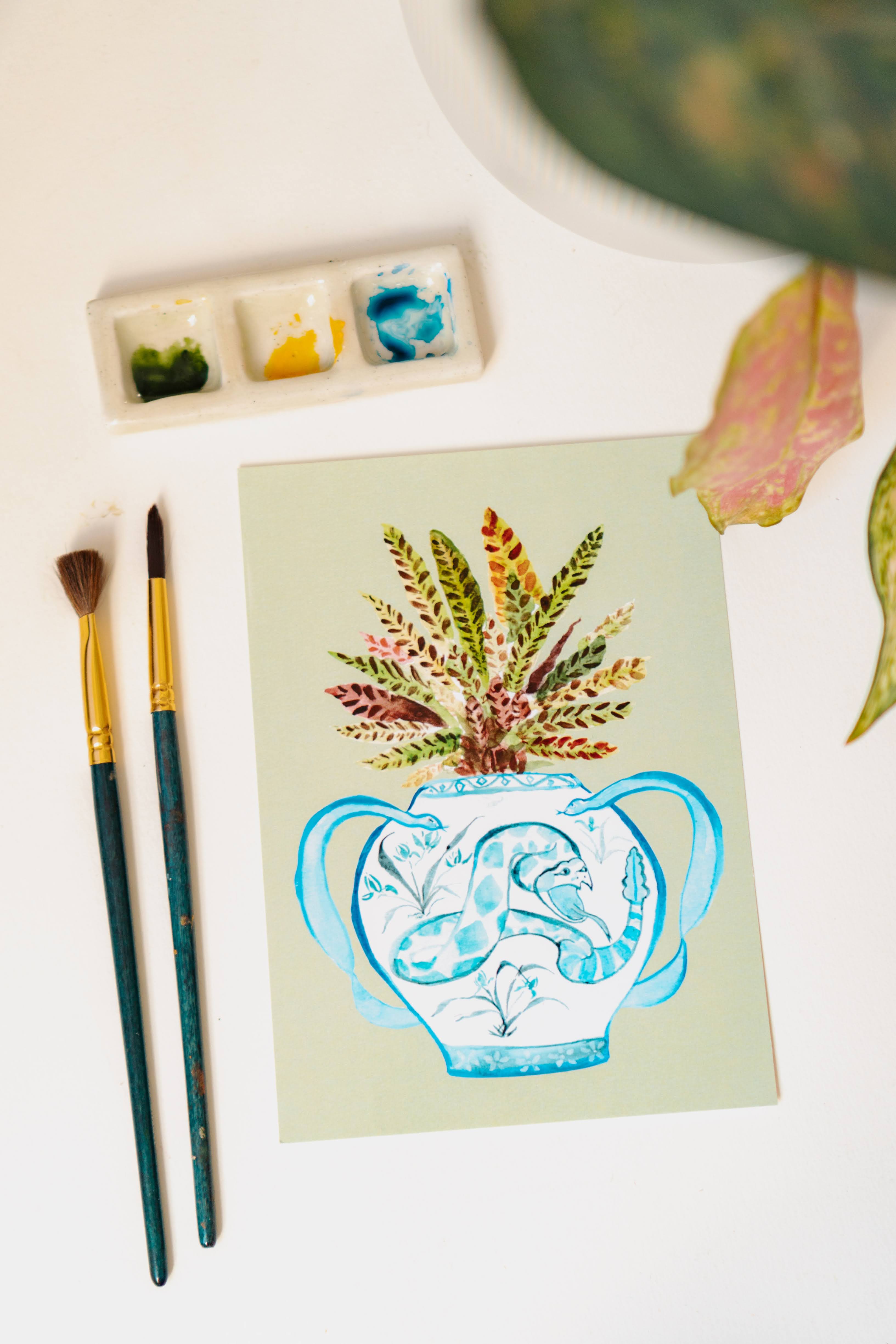 A print of a rattlesnake plant in a blue and white porcelain vase, decorated with a snake.