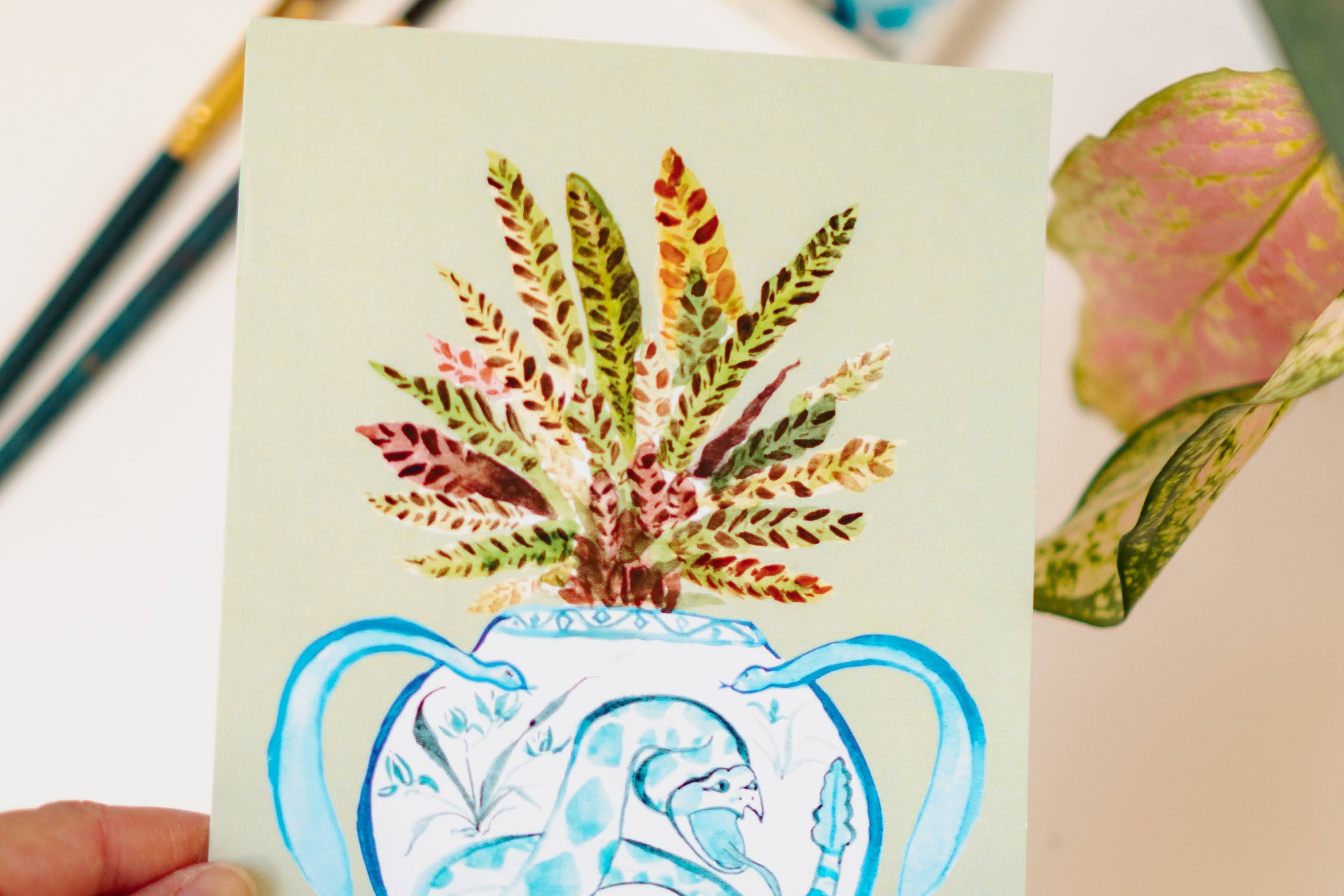 A print of a rattlesnake plant in a blue and white porcelain vase, decorated with a snake.