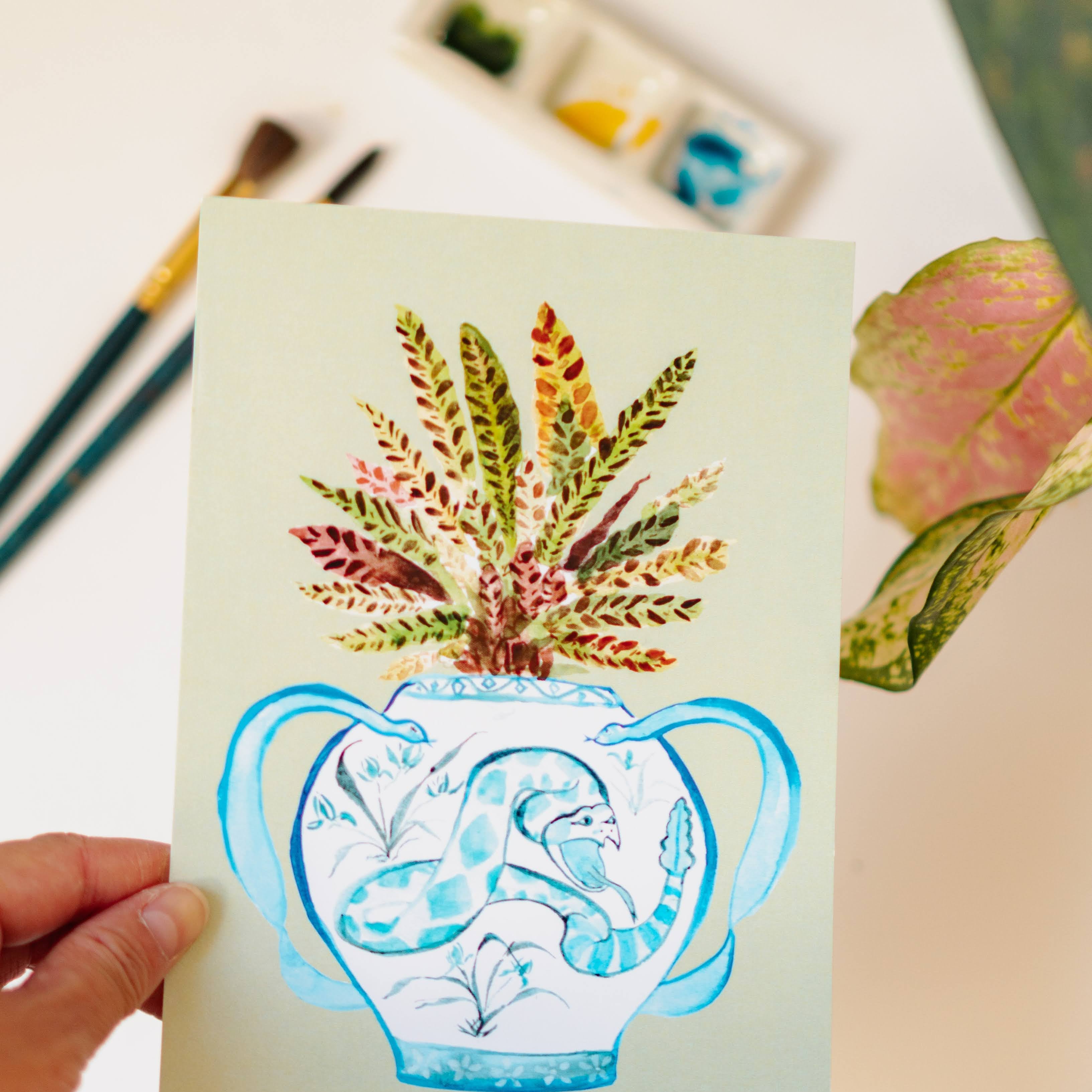 A print of a rattlesnake plant in a blue and white porcelain vase, decorated with a snake.