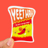 A sticker of a spicy bag of chips, drawn with red-yellow flames and smiling spicy foods, including a chili with sunglasses. "Yeet Hay" is written across the top of the bag, and below is written, "The best tasting food!"