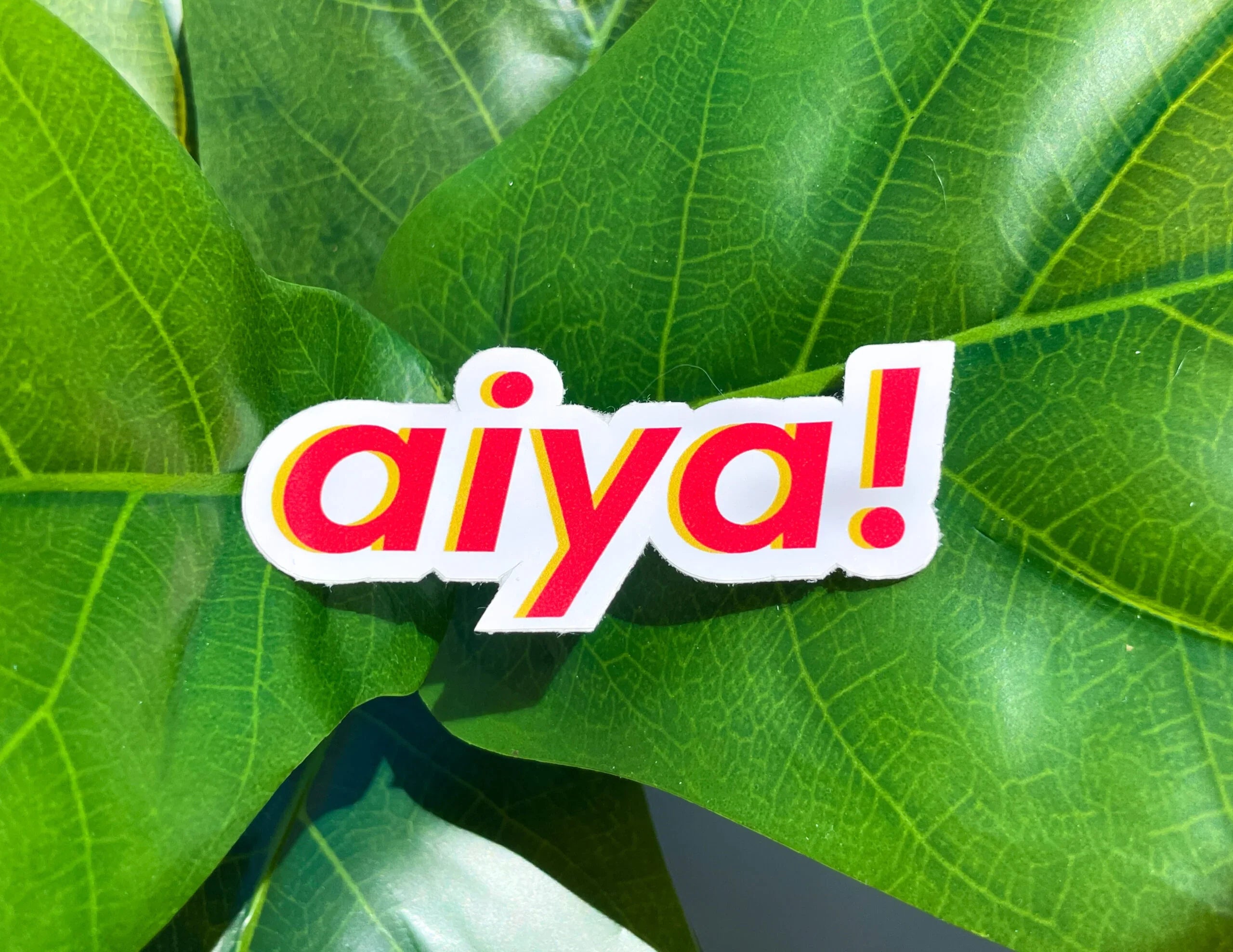 aiya! sticker on green leaf, whimsical AAPI-inspired design