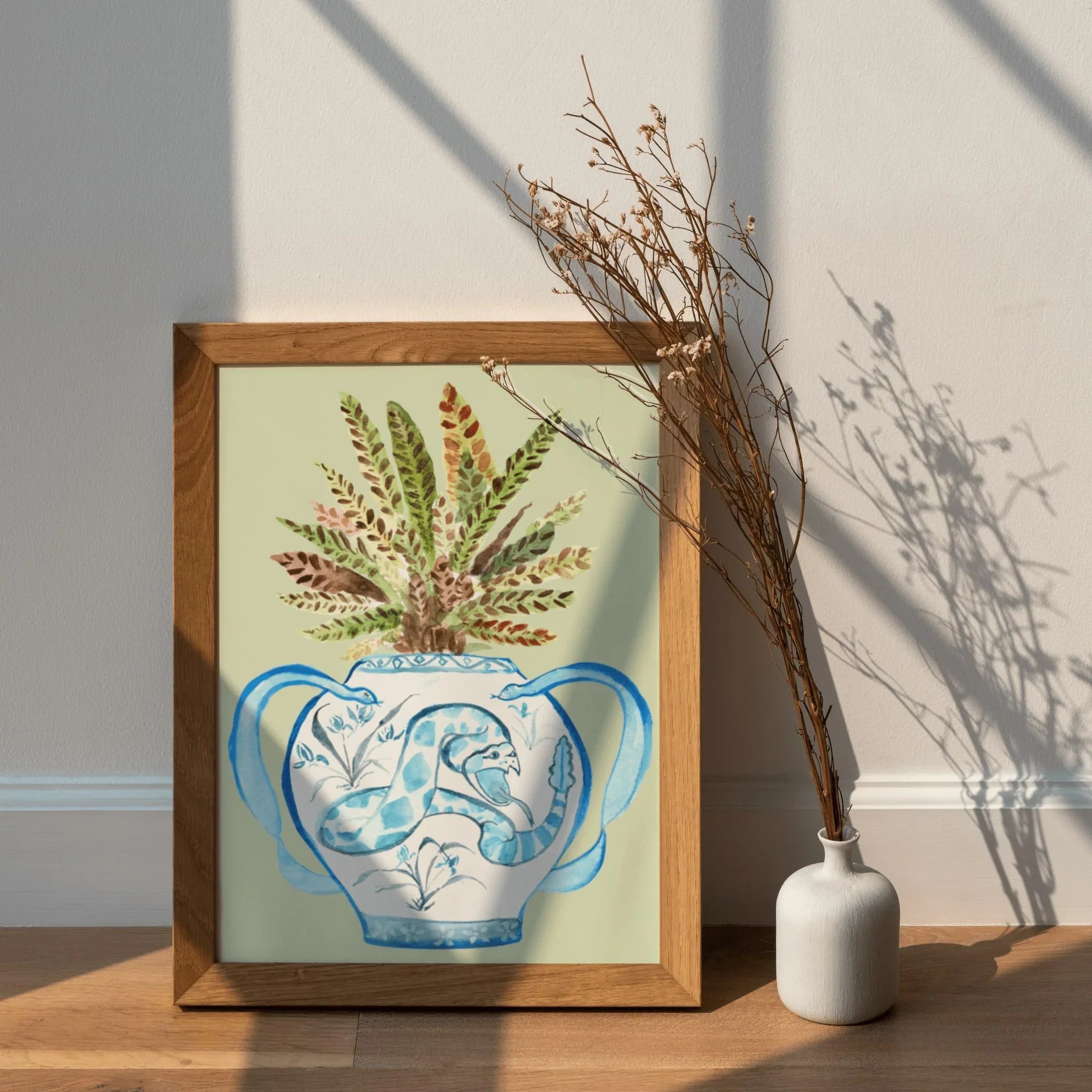 Framed art print of blue snake vase with fern, AAPI-inspired home decor, natural wood frame