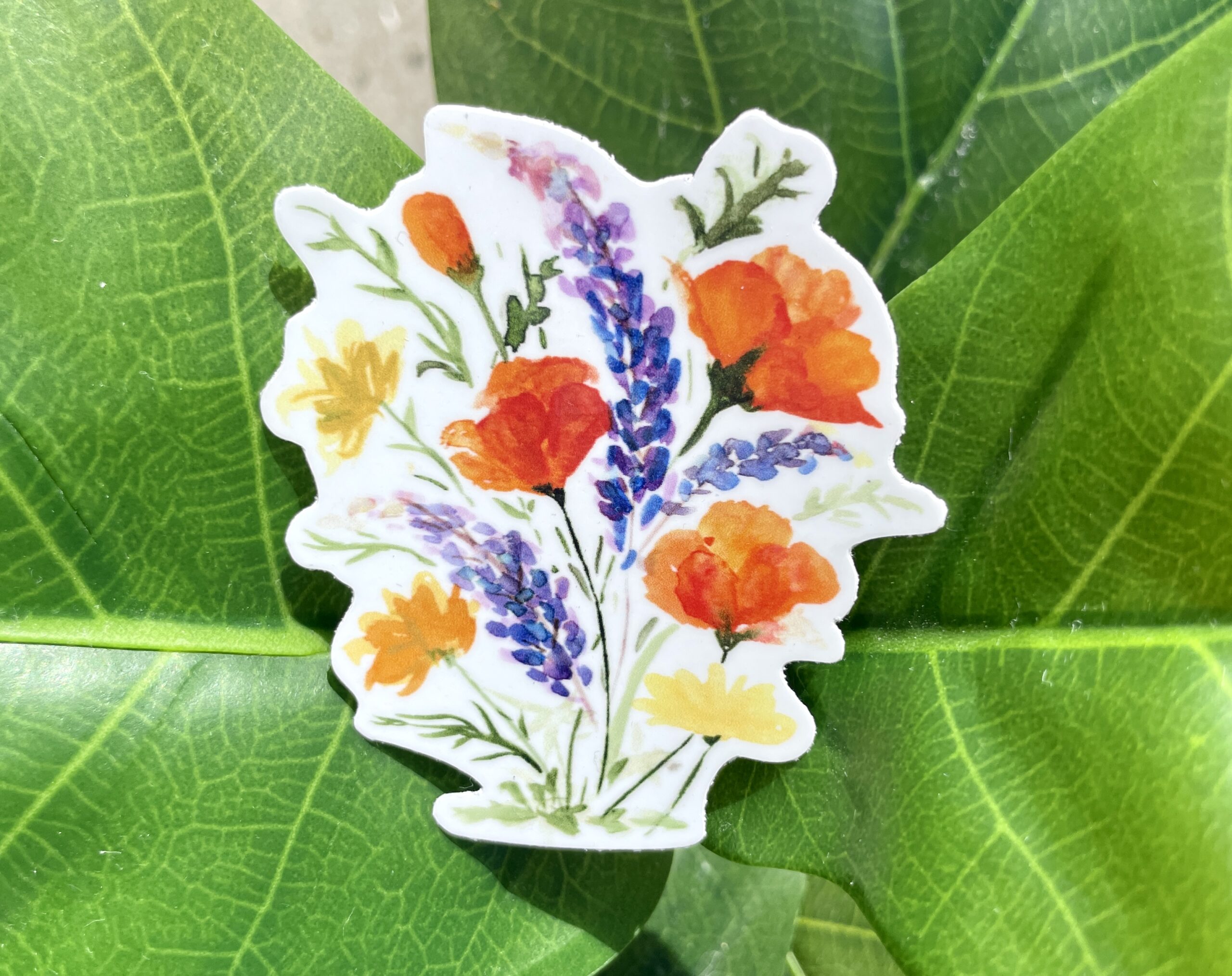 A white sticker of California poppies, California buttercups, and silver lupine.
