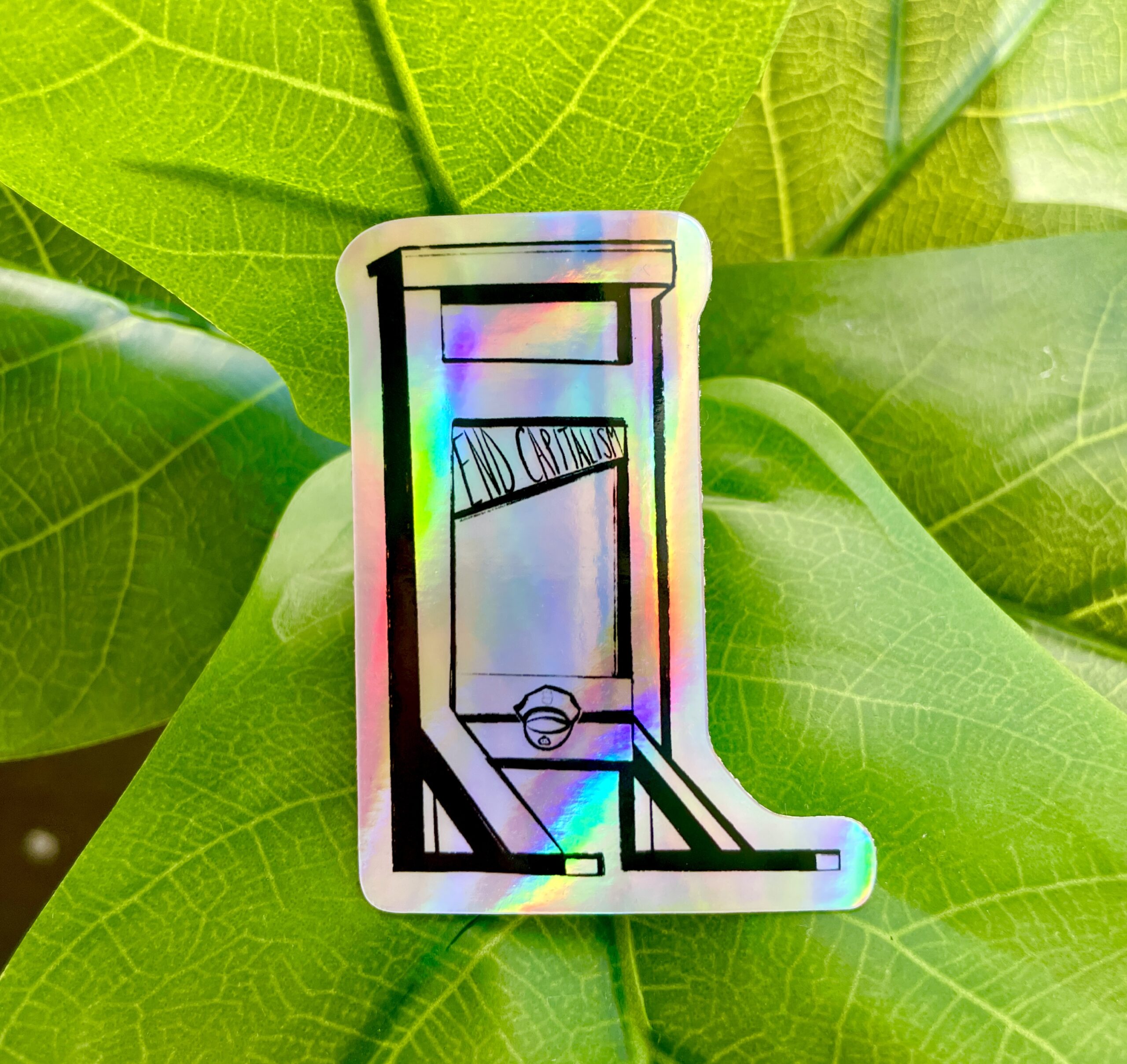 A holographic sticker of a guillotine, with the words "End Capitalism" written on the blade.