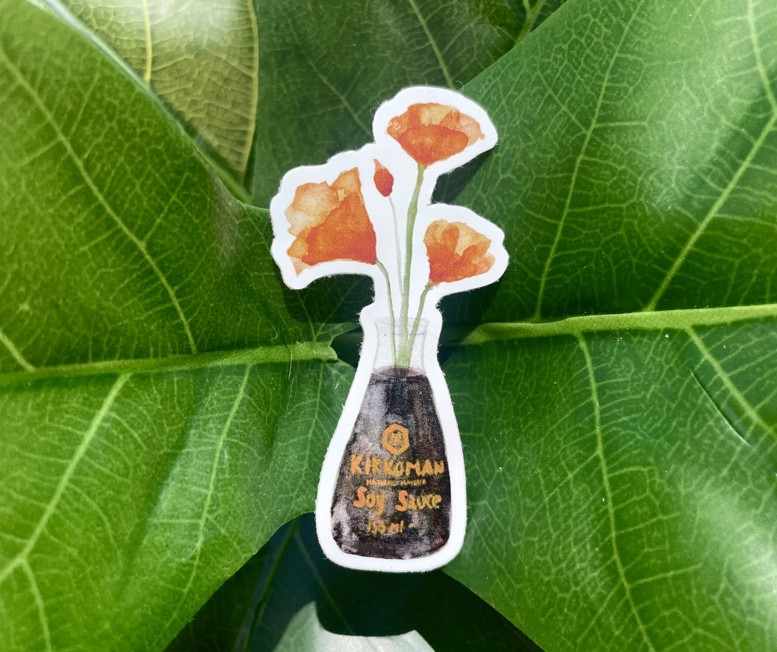 A white sticker of four orange California Poppies in a soy sauce bottle.