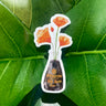 A white sticker of four orange California Poppies in a soy sauce bottle.