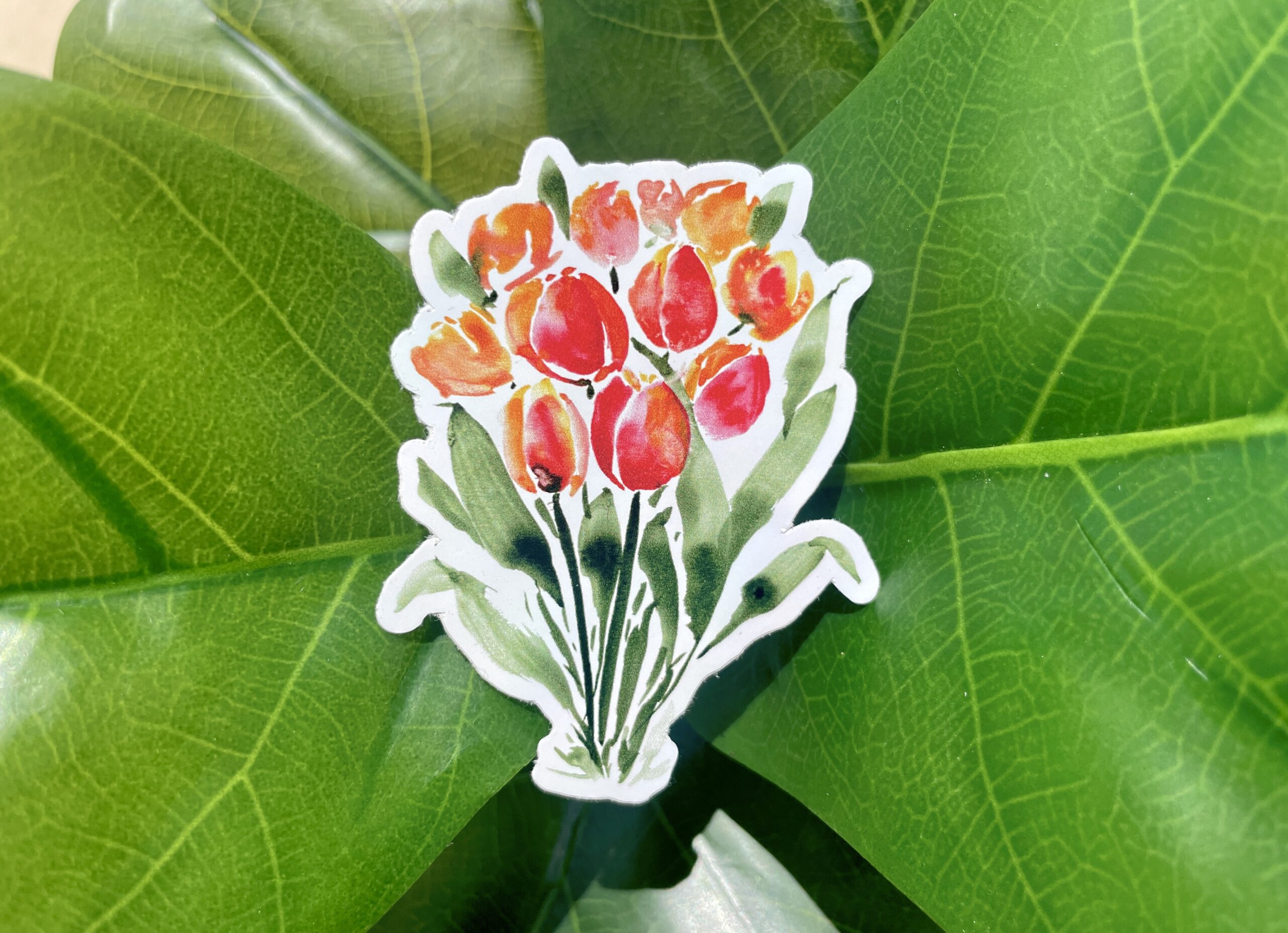 A sticker of orange and red watercolor tulips, standing on dark green stems.