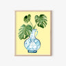 Framed art print with blue monkey vase and green monstera leaves on yellow background, AAPI-inspired home decor