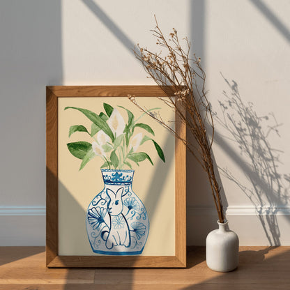 A print of a peace lily plant in a blue and white porcelain vase, decorated with a rabbit.