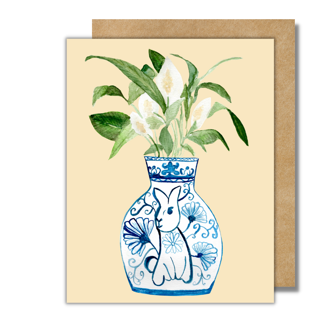 A greeting card featuring a peace lily plant in a blue and white porcelain vase, decorated with a rabbit.