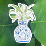 A sticker of a peace lily plant in a blue and white porcelain vase, decorated with a rabbit.