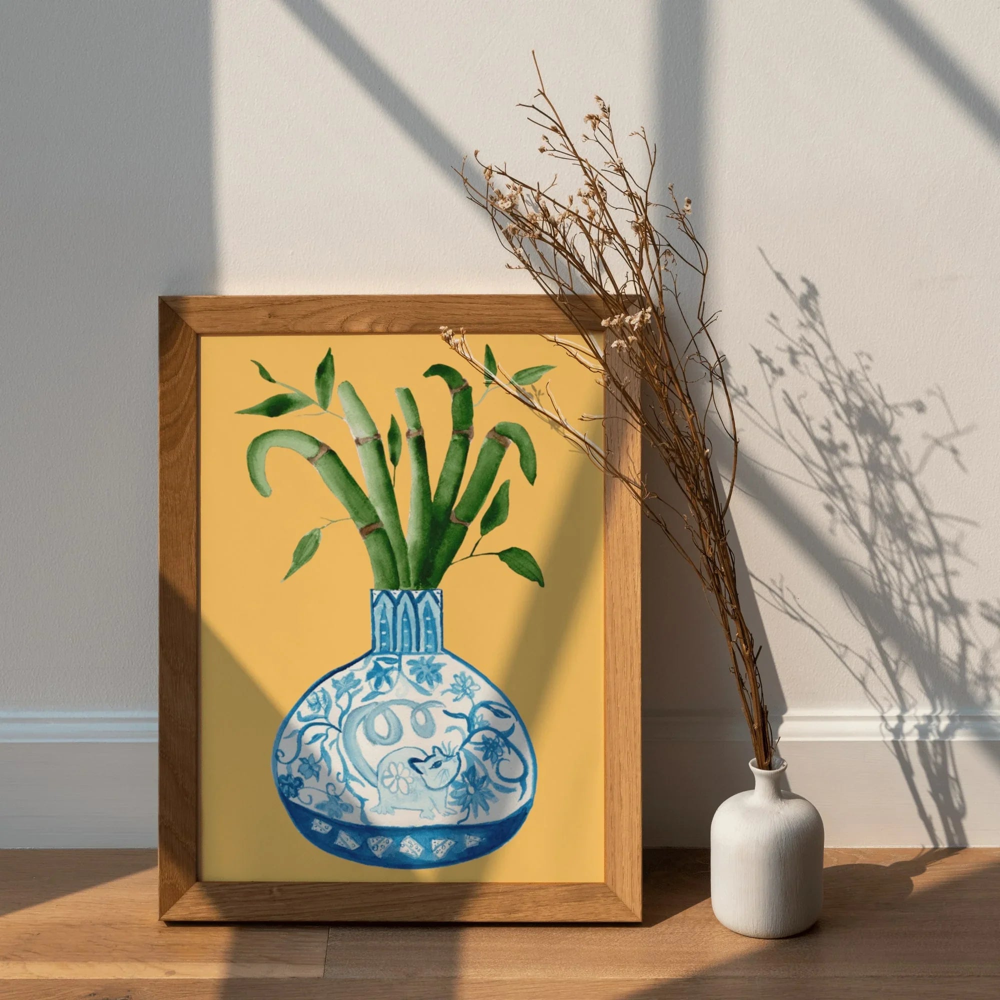 Framed art print of blue and white vase with bamboo, AAPI-inspired home decor, warm yellow background