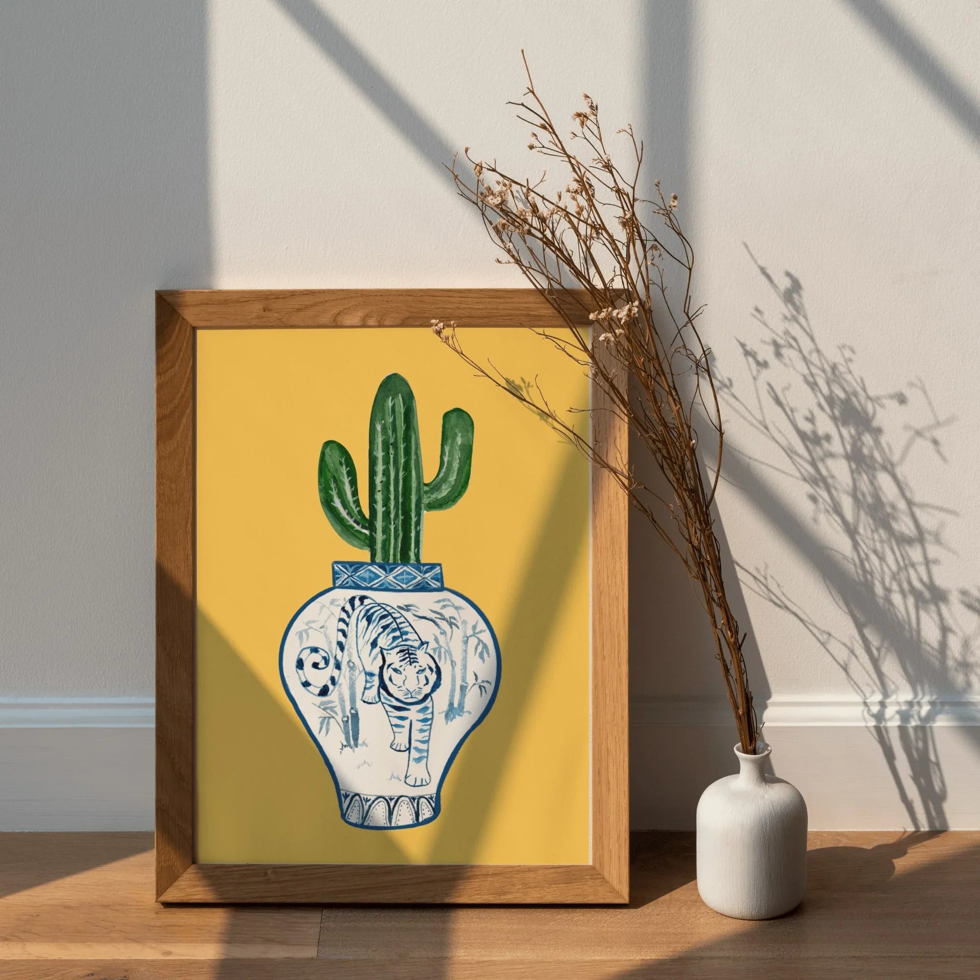 Framed art print with blue and white tiger vase holding green cactus, yellow background, modern home decor